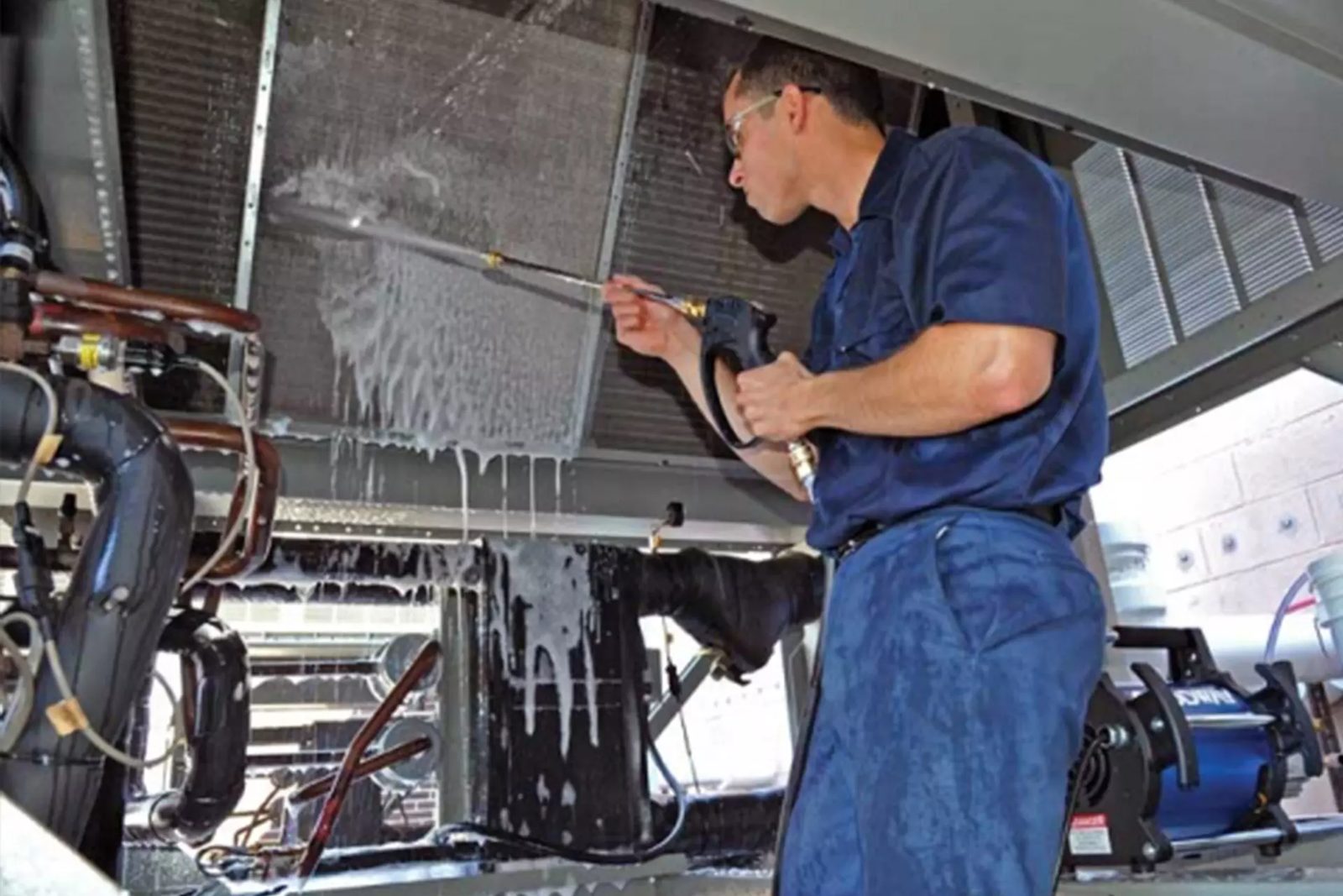 Technician washing an air conditioner coil with cleaning foam